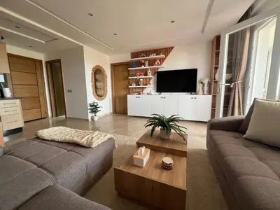 a living room with a couch and a tv at Appartement de luxe vue sur mer in Bouznika