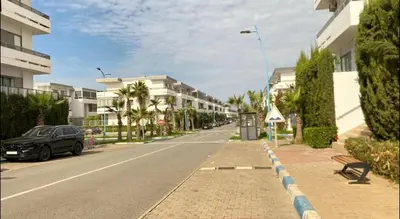 a street with buildings and a car parked on the road at Marbella beach in Mansouria