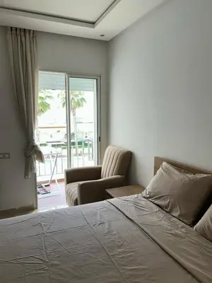 a bedroom with a bed and a chair and a window at Kettani Shems Bouznika in Bouznika