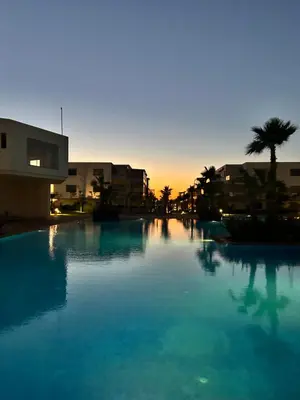 a large swimming pool with a sunset in the background at Sidi Rahal Blue Beach in El Jadida