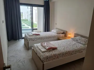 a hotel room with two beds and a window at Vakantie app charmante Harhoura in Temara
