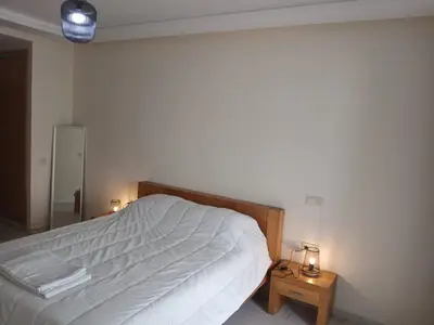 a bedroom with a white bed and two night stands at Vakantie app charmante Harhoura in Temara