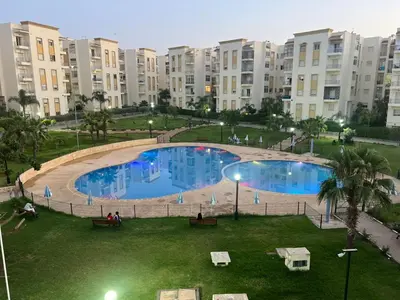 a large swimming pool in a park with large buildings at Beautiful 2 bedrooms apartment in Bouznika in Bouznika