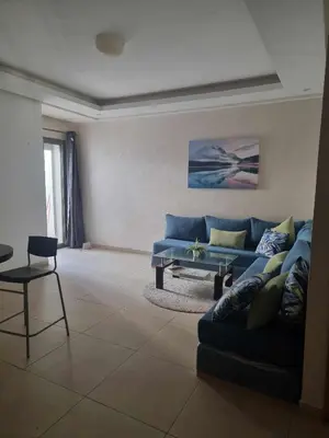 a living room with a blue couch and a table at Apparemment sur mer avec piscine al Mansouria in O Ben Slimane