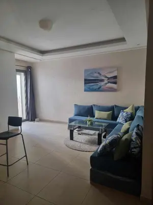 a living room with a blue couch and a table at Apparemment sur mer avec piscine al Mansouria in O Ben Slimane