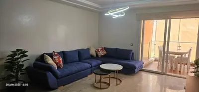 a living room with a blue couch and a table at Appartement tamaris in Sidi Rahal