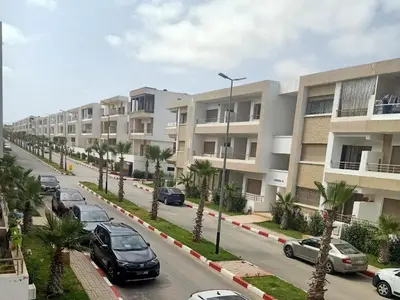 a street with cars parked in front of apartment buildings at Appartement Balneaire avec piscine à El Mansouria in Mansouria