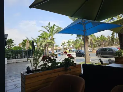a patio with a blue umbrella and a parking lot at Appartement Balneaire avec piscine à El Mansouria in Mansouria