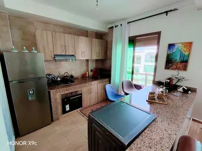 a kitchen with a refrigerator and a counter with chairs at appartement avec piscines in Mansouria