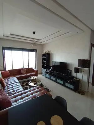 a living room with a couch and a television at Charming appartement in Bouznika in Bouznika