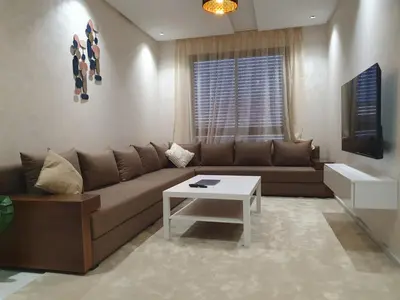 a living room with a brown couch and a table at Studio Parc Mohammedia in Mohammedia