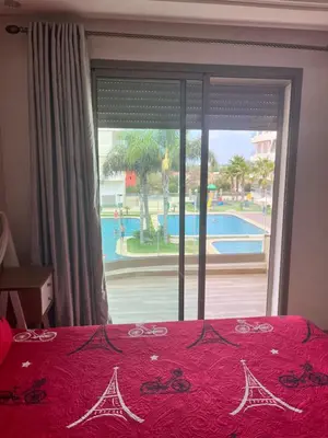 a bedroom with a window with a view of a pool at Belle Appt vue sur Piscine à Bouznika plage in Bouznika