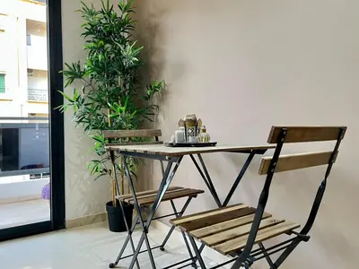 a table and two chairs in a room with plants at Rihla Stays - Anfa City in Casablanca