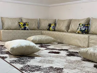 a living room with a couch with pillows on a rug at Duplex - Pool and Beach in Dar Hamida
