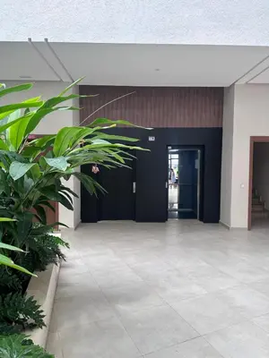 an empty lobby with black doors and green plants at Appartement moderne avec piscine, 2 chambres in Bouznika