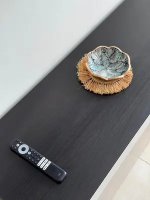 a remote control sitting on a table next to a bowl at Appartement moderne avec piscine, 2 chambres in Bouznika