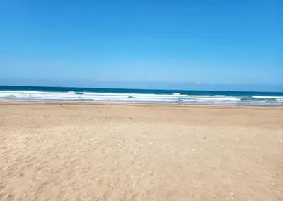 a sandy beach with the ocean in the background at Blue beach in Bir Jedíd Saint-Hubert