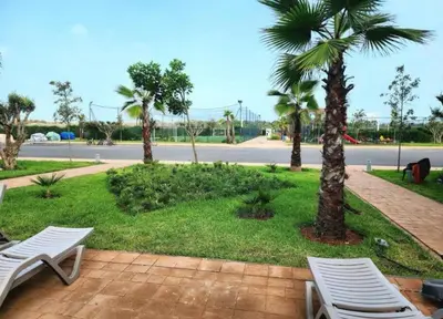 a patio with two white chairs and palm trees at Blue beach in Bir Jedíd Saint-Hubert