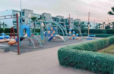 a playground in a park with a play equipment at Appt moderne 3 chbr Blanca Beach in Sidi Rahal