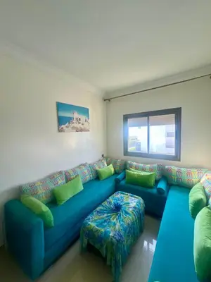 a living room with a blue couch and green pillows at Appt moderne 3 chbr Blanca Beach in Sidi Rahal