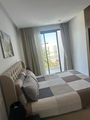 a man laying on a bed in a room with a window at Charming Studio in Oasis in Oulad Akkou