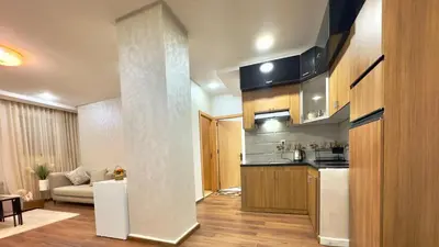 a kitchen with wooden cabinets and a living room at 1min walk B&B City Center in Casablanca