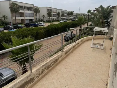 a metal railing on a balcony with a parking lot at Savannah beach in Dar Hamida