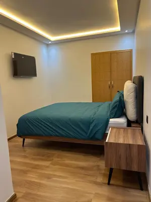 a bedroom with a bed and a tv and a table at Magnifique appartement 2 chambres vue sur piscine - Sidi Rahal in Sidi Rahal
