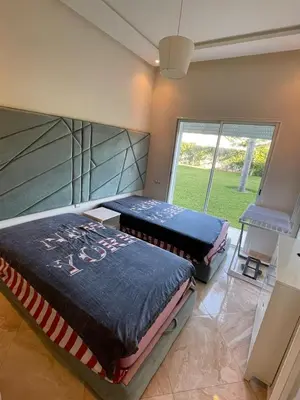 two beds in a room with a large window at Appartement casa bay sidi rahel in Sidi Rahal