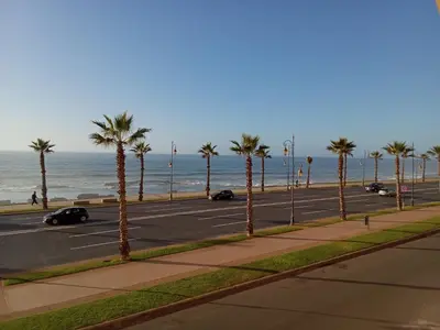 a parking lot with palm trees and the ocean at Chez Basma in Rabat