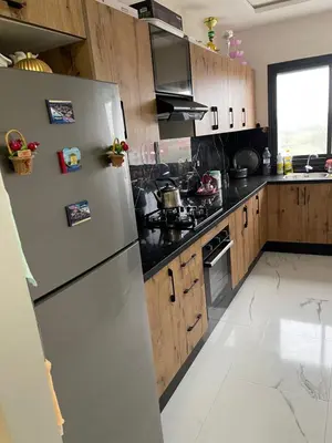 a kitchen with a white refrigerator and wooden cabinets at Apparemment propre pour location pour les familles in Casablanca