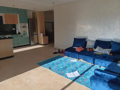 a living room with a blue couch and a rug at Location de vacances 3 chambres in Mansouria