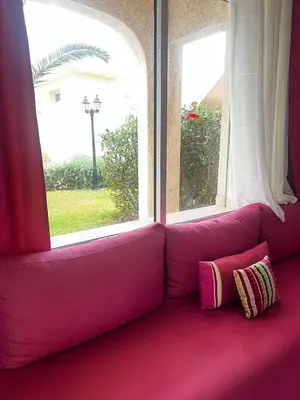 a pink couch in a room with two windows at Villa près de la mer, sidi rahal route de dar bouazza in Bir Jedíd Saint-Hubert