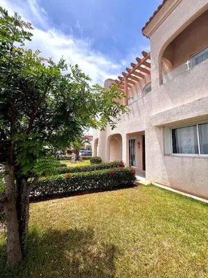 a building with a tree in front of a yard at Villa près de la mer, sidi rahal route de dar bouazza in Bir Jedíd Saint-Hubert