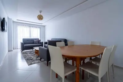 a dining room with a wooden table and chairs at Appartement Moderne avec Piscine in Bouznika