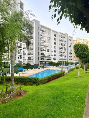 an apartment building with a swimming pool in a park at Elegant & Spacious Apartment in Prestigia in Rabat