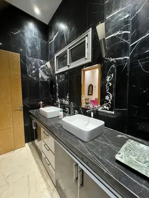 a bathroom with two sinks and a black tiled wall at Farm with villa and pool in Settat