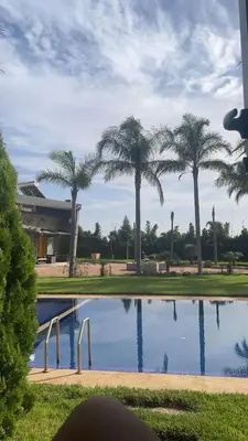 a pool with palm trees in front of a building at Farm with villa and pool in Settat