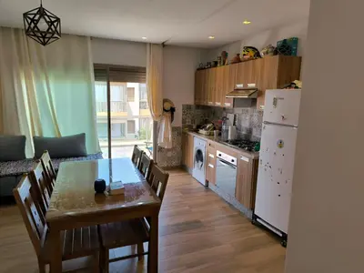 a kitchen and dining room with a table and a refrigerator at Les Sables de Sidi Rahal - Blue Beach in Sidi Rahal