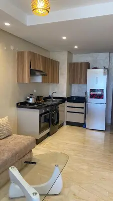 a kitchen with a couch and a white refrigerator at Studio calme à Zenata in Aïn Harrouda