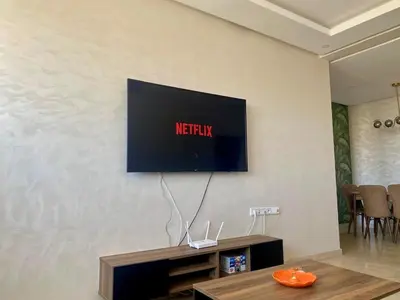 a television on a wall in a living room at Sunny 2-Bedroom Apartment with Pool for a Great Stay in Mohammedia