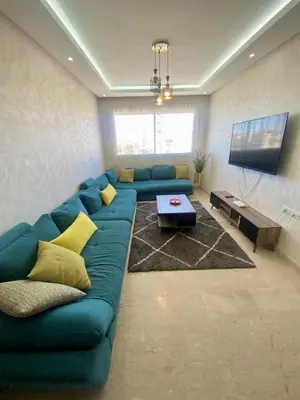 a living room with a blue couch and a table at Sunny 2-Bedroom Apartment with Pool for a Great Stay in Mohammedia