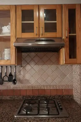 a stove top in a kitchen with wooden cabinets at Cosy Loft - 2 Bedrooms & Parking - Agdal Center in Rabat