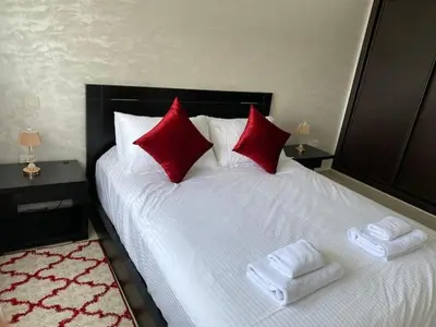 a bed with two red pillows and towels on it at Appartement Spacieux & Moderne, 2 min Gare, 10 min Plage, Parking Gratuit in Casablanca
