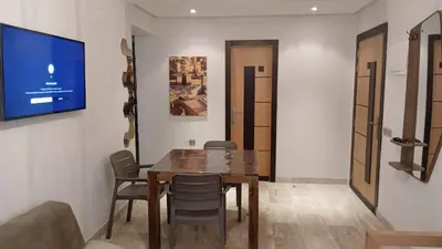 a dining room with a table and chairs and a tv at Macha allah in Bouznika