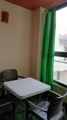 a table and chairs in a room with a green curtain at Macha allah in Bouznika