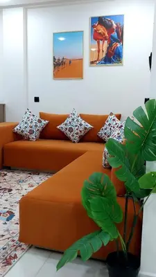 an orange couch in a living room with a plant at Studio Marzouga in Deroua
