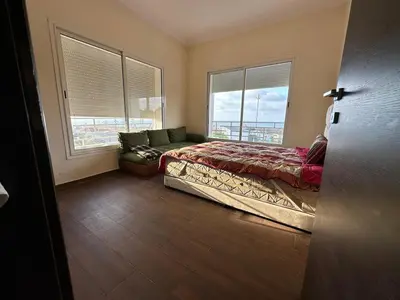 a bedroom with a bed and a couch and windows at Beach flat with pool at Al Mansouria in O Ben Slimane