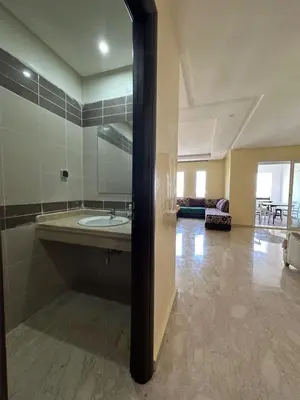 a large bathroom with a sink and a living room at Beach flat with pool at Al Mansouria in O Ben Slimane