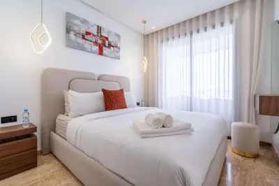 a bedroom with a large white bed with towels on it at Appartement avec Piscine dans Résidence Privée in Dar Bouazza